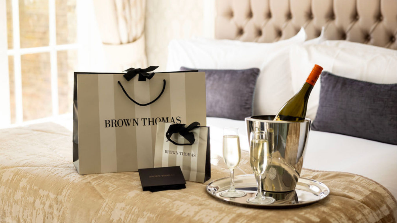 Luxurious hotel room with champagne tray, plush bedding, and elegant shopping bags; ideal for a relaxing stay.